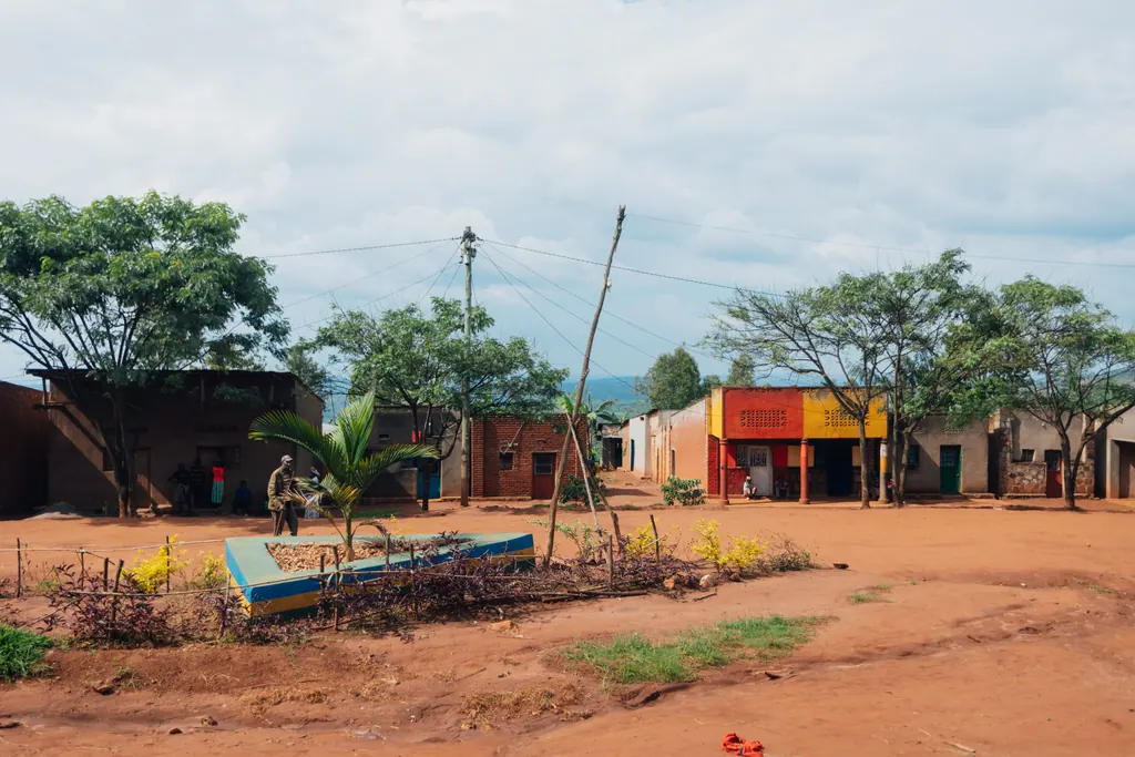 A wide village square of red earth lined with small shops in Kirehe.